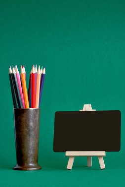 Metal bir stand üzerinde minyatür tebeşir tahtası yeşil arka plan üzerinde izole, okula geri kavram, seçici odak