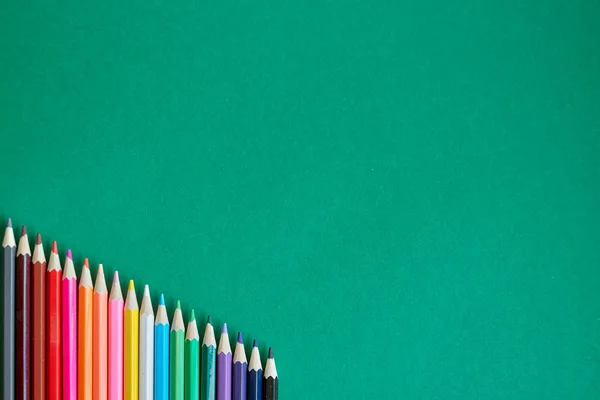 Ansicht von Farbstiften in Regenbogenfarben isoliert auf grünem Hintergrund, Konzept zurück zur Schule, selektiver Fokus — Stockfoto