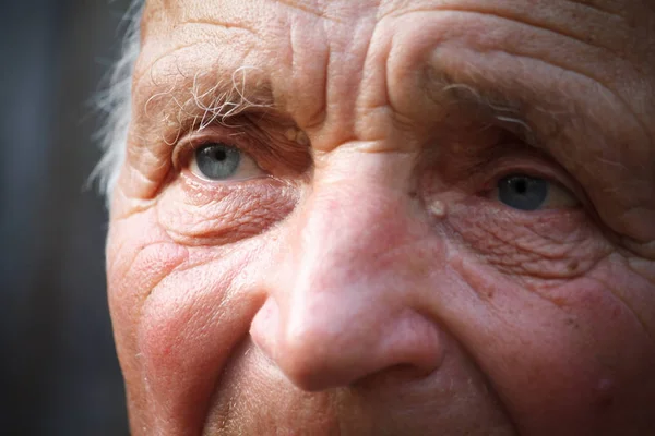 Close-up portrait of a very old man against the background of wattle, selective focus — Stock Photo, Image