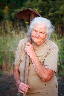 Close-up portrait of an old woman with gray hair smiling and looking at the camera, holding a rusty shovel in her hands, face in deep wrinkles, selective focus clipart