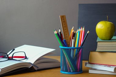 Geri okul kavramı, okul malzemeleri, kitap yığını, tebeşir tahtası ve ahşap bir yüzey üzerinde gözlük ile açık kitap, seçici odak