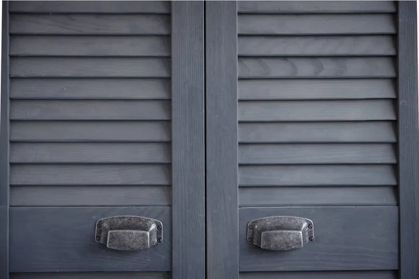 Gros plan portes à volets gris foncé avec poignées métalliques effilochées, intérieur scandinave minimaliste, mise au point sélective — Photo