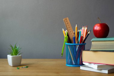Geri okul kavramı, okul malzemeleri, kitap yığını, kırmızı elma ve ahşap bir yüzey üzerinde beyaz bir tencerede sulu, seçici odak