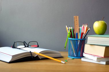 Geri okul kavramı, okul malzemeleri, kitap yığını, yeşil elma ve ahşap bir yüzey, seçici odak gözlük ile açık kitap