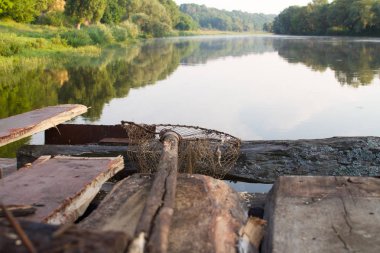 Eski bir ev yapımı balıkçılık iniş ağı yakın çekim geniş bir nehir, seçici odak arka plan karşı eski bir ahşap iskele üzerinde yatıyor