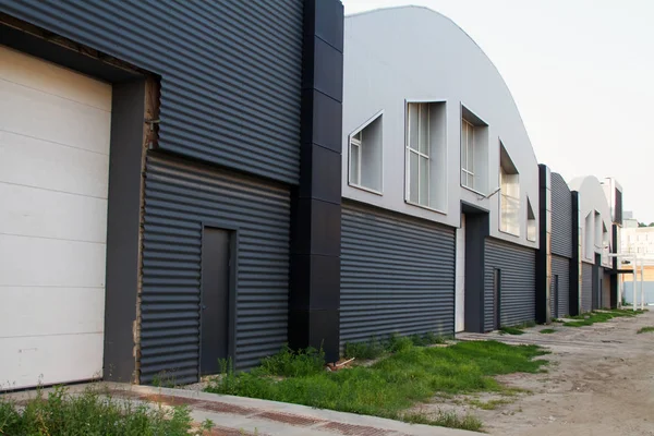 Edificios industriales grises de talleres o almacenes con portones elevadores, puertas y ventanas, copyspace — Foto de Stock