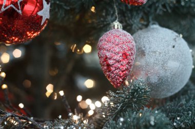 Yakın çekim beyaz, kırmızı noel topları ve noel ağacı dalları üzerinde altın çelenk ile kırmızı koni ladin, seçici odak