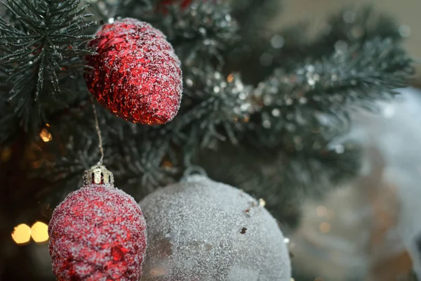 Primer plano bolas de navidad blancas con abetos de cono rojo en ramas de árbol de navidad, enfoque selectivo — Foto de Stock
