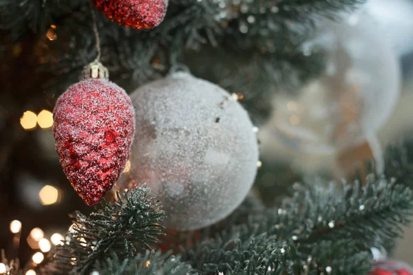 Primer plano bolas de Navidad blancas con abeto cono rojo en ramas de árbol de Navidad, enfoque selectivo — Foto de Stock
