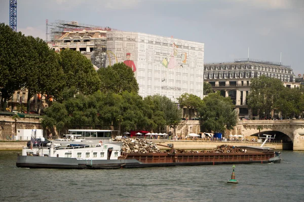 Una chiatta con zattere di rottami metallici lungo la Senna sullo sfondo del centro storico di Parigi — Foto Stock