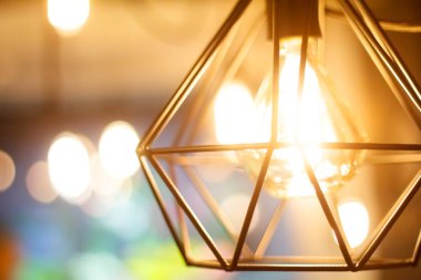 Bulanık diğer lambaların arka planına karşı yakın çekim parlayan asılı küresel retro vintage edison akkor ampul, seçici odak