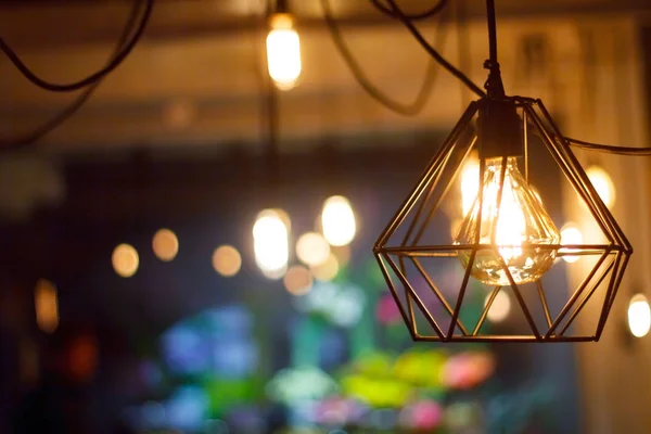 Närbild glödande hängande sfäriska Retro vintage Edison glödlampa mot bakgrund av suddiga andra lampor, selektiv fokus — Stockfoto