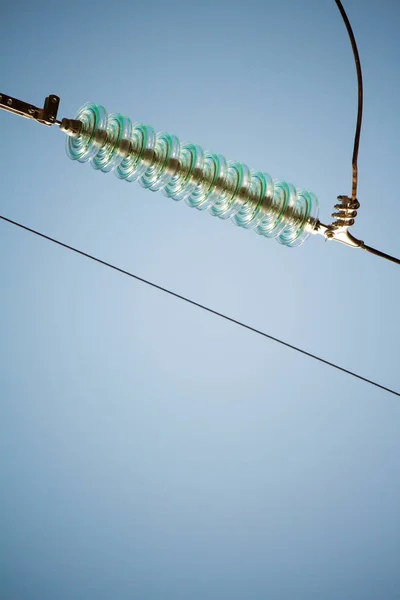 Visão de fundo de close-up de isoladores em fios de alta tensão em uma torre de energia contra um céu azul — Fotografia de Stock