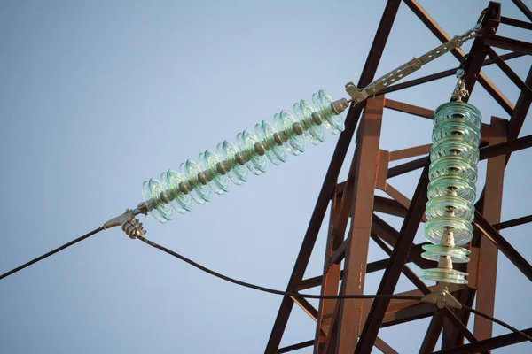 Visão de fundo de close-up de isoladores em fios de alta tensão em uma torre de energia contra um céu azul — Fotografia de Stock