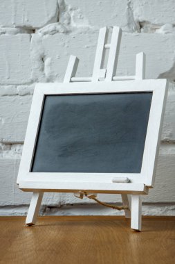 Beyaz tuğla duvar arka plan üzerinde tebeşir lekeleri ve tebeşir ile minyatür bir tebeşir tahtası yakın çekim, seçici odak