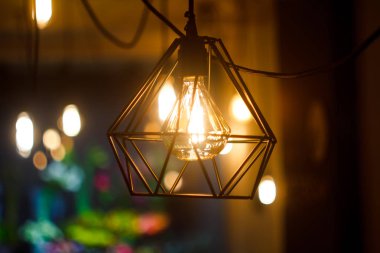 Bulanık diğer lambaların arka planına karşı metal abajur da yakın çekim parlayan asılı küresel retro vintage edison akkor ampul, seçici odak