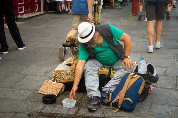 Homeless and his dog are sitting on the sidewalk of the streets of Paris at the feet of passing tourists and Parisians and asking for alms — Stock Photo, Image