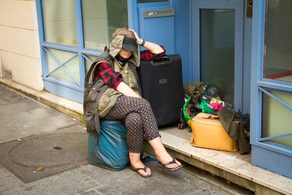 Homeless woman with bags and a suitcase on a street sidewalk in Paris — Stock Photo, Image