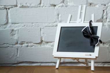 Beyaz tuğla duvar arka plan üzerinde minyatür tebeşir tahtası ve papyon yakın çekim, seçici odak