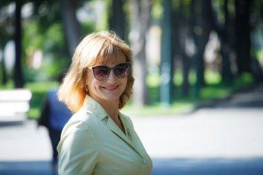 Olgun orta yaşlı kadın parkta bir yürüyüş kameraya gülümseyen, seçici odak