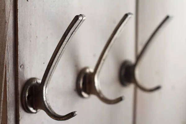 Close-up of three empty metal hooks on a white wooden wall, selective focus — Stock Photo, Image