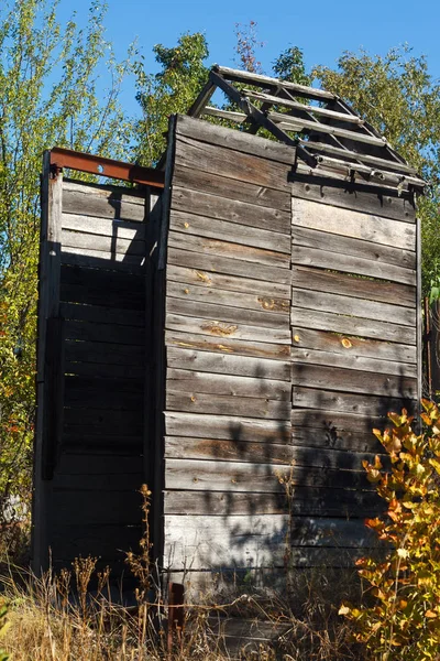 Zničená dřevěná stodola na opuštěném poli v okoralé trávě a podzimních stromech, selektivní zaměření — Stock fotografie