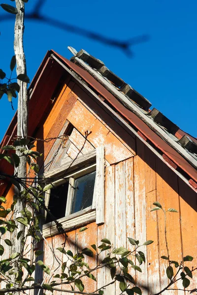 Stará dřevěná střecha se schodištěm a oknem malého venkovského domu na pozadí modrého nebe — Stock fotografie