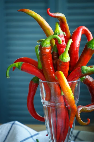Zbliżenie bukiet długich czerwonych papryki chili w rocznika szklany kieliszek na naturalnym obrus, selektywne skupienie — Zdjęcie stockowe