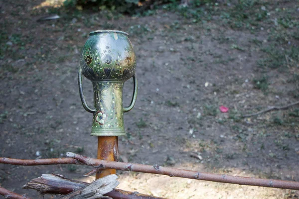 Une cruche en métal avec deux poignées suspendues à un poteau de clôture, mise au point sélective — Photo