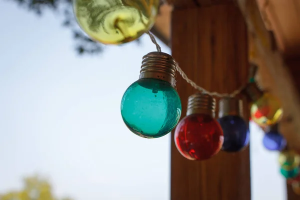 Close-up van een slinger van multi-gekleurde gloeilampen, decor van de buiten veranda, selectieve focus — Stockfoto