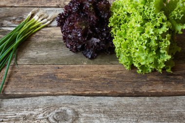 Eski pürüzlü ahşap yüzey, sağlıklı beslenme konsepti, seçici odak üzerinde kök ve genç soğan demet ile yeşil ve kırmızı taze marul