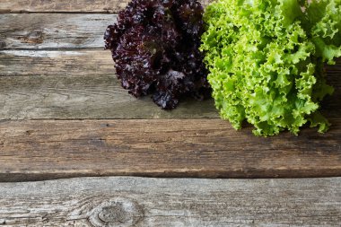 Eski pürüzlü ahşap yüzeyde yeşil ve kırmızı taze marul, sağlıklı beslenme konsepti, seçici odak