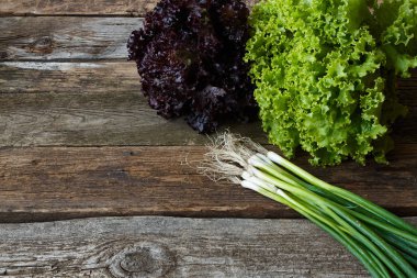Eski pürüzlü ahşap yüzey, sağlıklı beslenme konsepti, seçici odak üzerinde kök ve genç soğan demet ile yeşil ve kırmızı taze marul