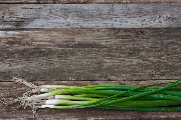 Bunch of young onions on an old rough wooden surface, healthy eating concept, selective focus — Stock Photo, Image