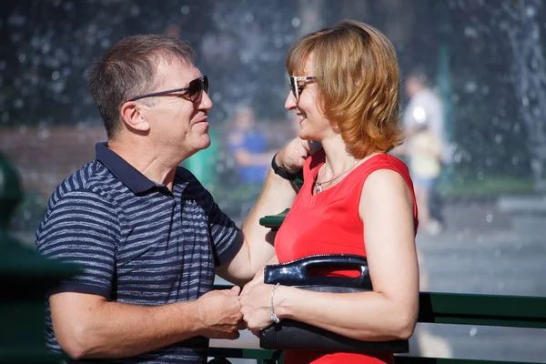 Пара средних лет улыбается и обнимается на прогулке в общественном месте — стоковое фото