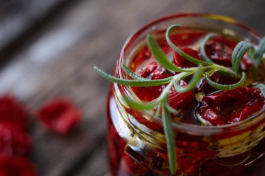 Son derece yakın bir rustik ahşap yüzey, seçici odak üzerinde Provencal otlar, sarımsak ve zeytinyağı ile ev yapımı güneşte kurutulmuş domates kavanoz