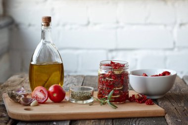 Rustik ahşap yüzeyde Provencal otlar, sarımsak ve zeytinyağı ile güneşte kurutulmuş domates, seçici odak