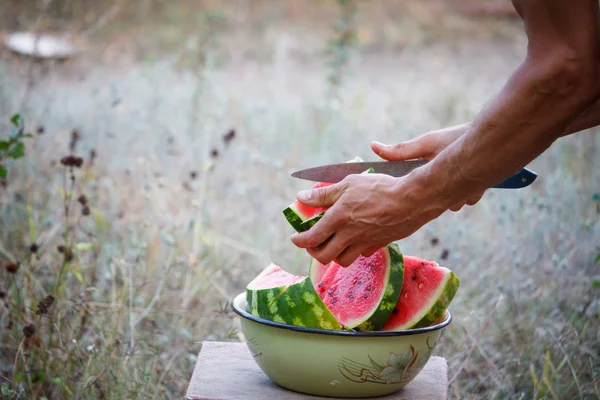 Hommes mains coupées pastèque mûre en tranches, pique-nique à l'extérieur, mise au point sélective — Photo