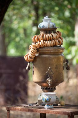 Üzerinde bir çaydanlık ve çay için bir fincan, seçici odak ile eski bir bronz ahşap yanan samovar üstüne simit bir demet