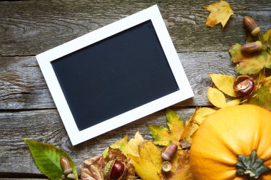 Şükran Günü sonbahar arkaplanı koyu ahşap bir zemin, kabaklar, kurumuş yapraklar, meşe palamutları, kestaneler ve yazıtlar için bir çerçeve, seçici odaklanma.