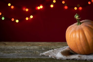 Koyu ahşap bir yüzeyde sonbahar arkaplanı bulanık ışıkların arka planında turuncu balkabağı, seçici odak