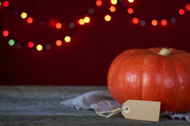 Koyu ahşap bir yüzeyde sonbahar arkaplanı bulanık ışıkların arka planında turuncu balkabağı, seçici odak