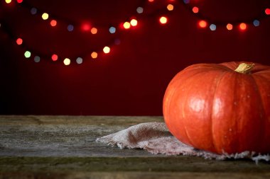 Koyu ahşap bir yüzeyde sonbahar arkaplanı bulanık ışıkların arka planında turuncu balkabağı, seçici odak