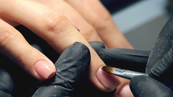 专业指甲护理过程中 美容师在黑色手套使指甲女客户用多凝胶盖修甲 — 图库视频影像