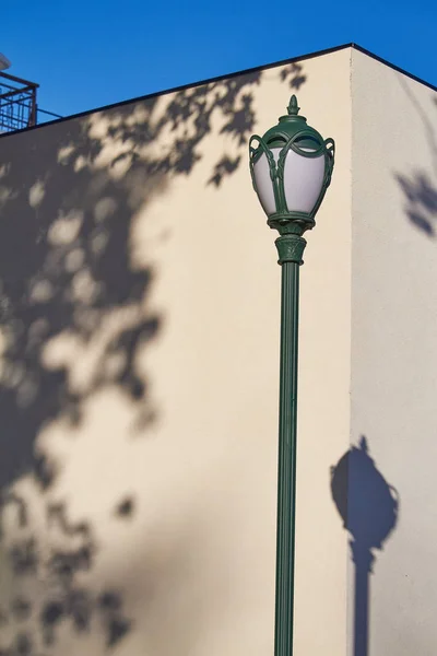 Lâmpada de rua e sua sombra em um fundo de parede branco — Fotografia de Stock