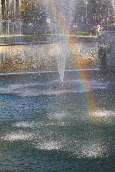 Реактивный фонтан и радуга над фонтаном в городском парке, избирательный фокус — стоковое фото
