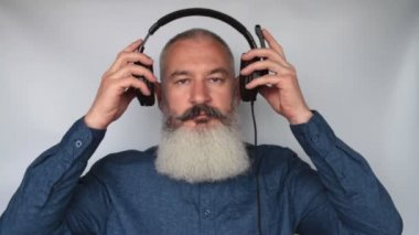 Çağrı merkezi çalışanı kafasına kulaklık takar, olgun beyaz sakallı adam kulaklığını takar, mutlu ve mutlu görünür..
