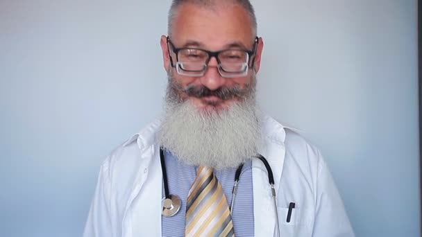 Allegro maturo medico maschio barbuto mette su due bicchieri e guarda attraverso una lente.. Trattamento o concetto di miglioramento della vista. Fondo grigio . — Video Stock