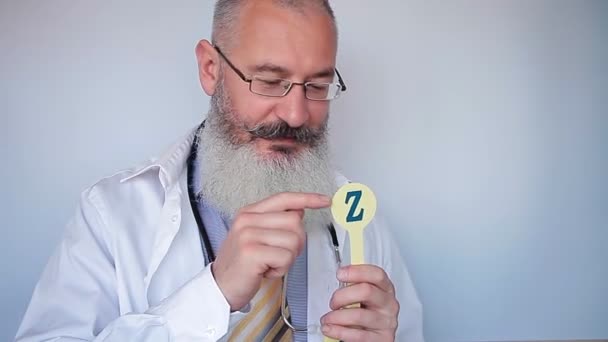 Starší vousatý řečový terapeut ukazuje písmeno Z a vysvětluje, jak to správně vyslovit. Dobrý doktor. Šedé pozadí. — Stock video