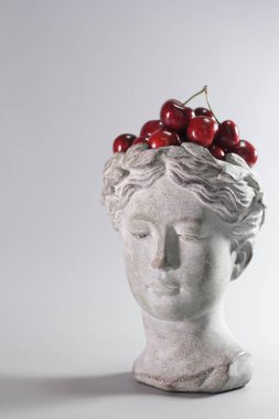Kırmızı kirazlarla dolu Yunan tanrıçası şeklindeki şık dekorasyon. Güzel tasarım elemanları. Gri arkaplan.